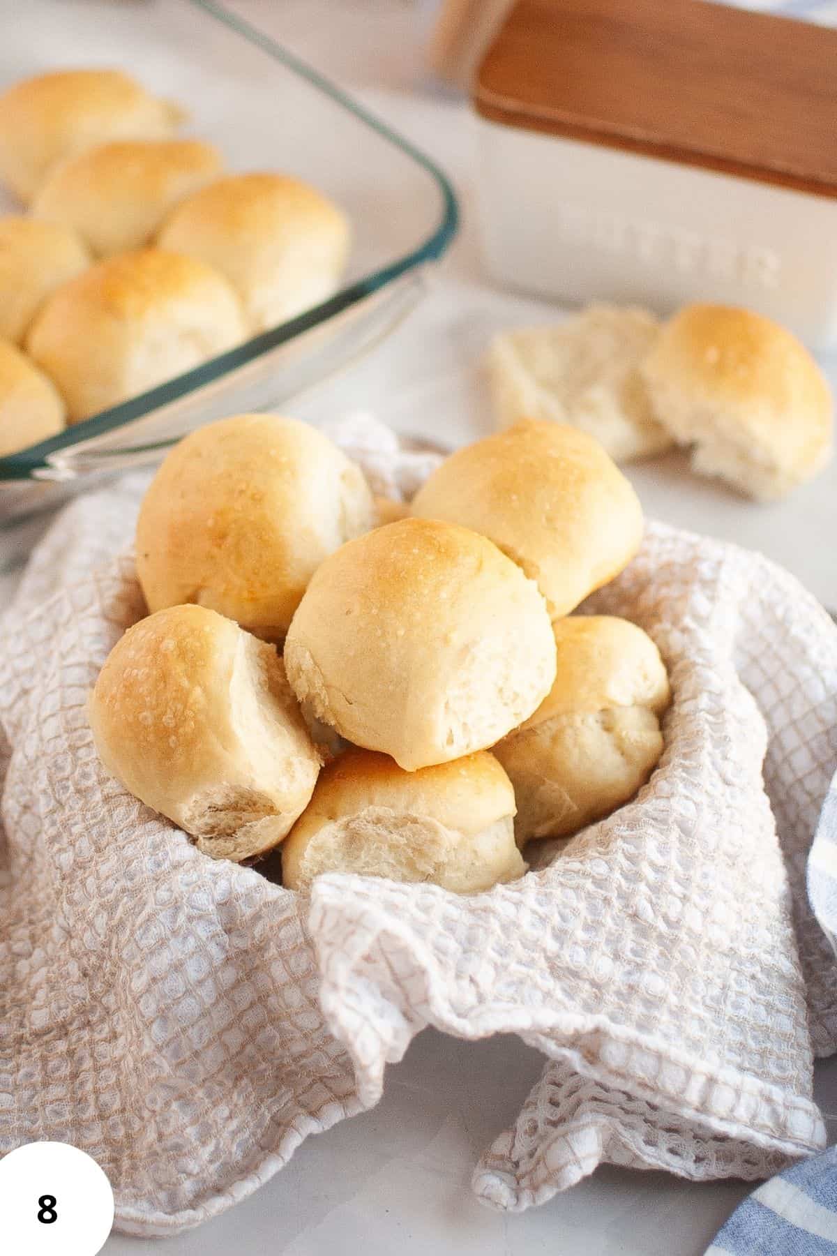 A basket lined with cloth filled with stacked sourdough brioche rolls.