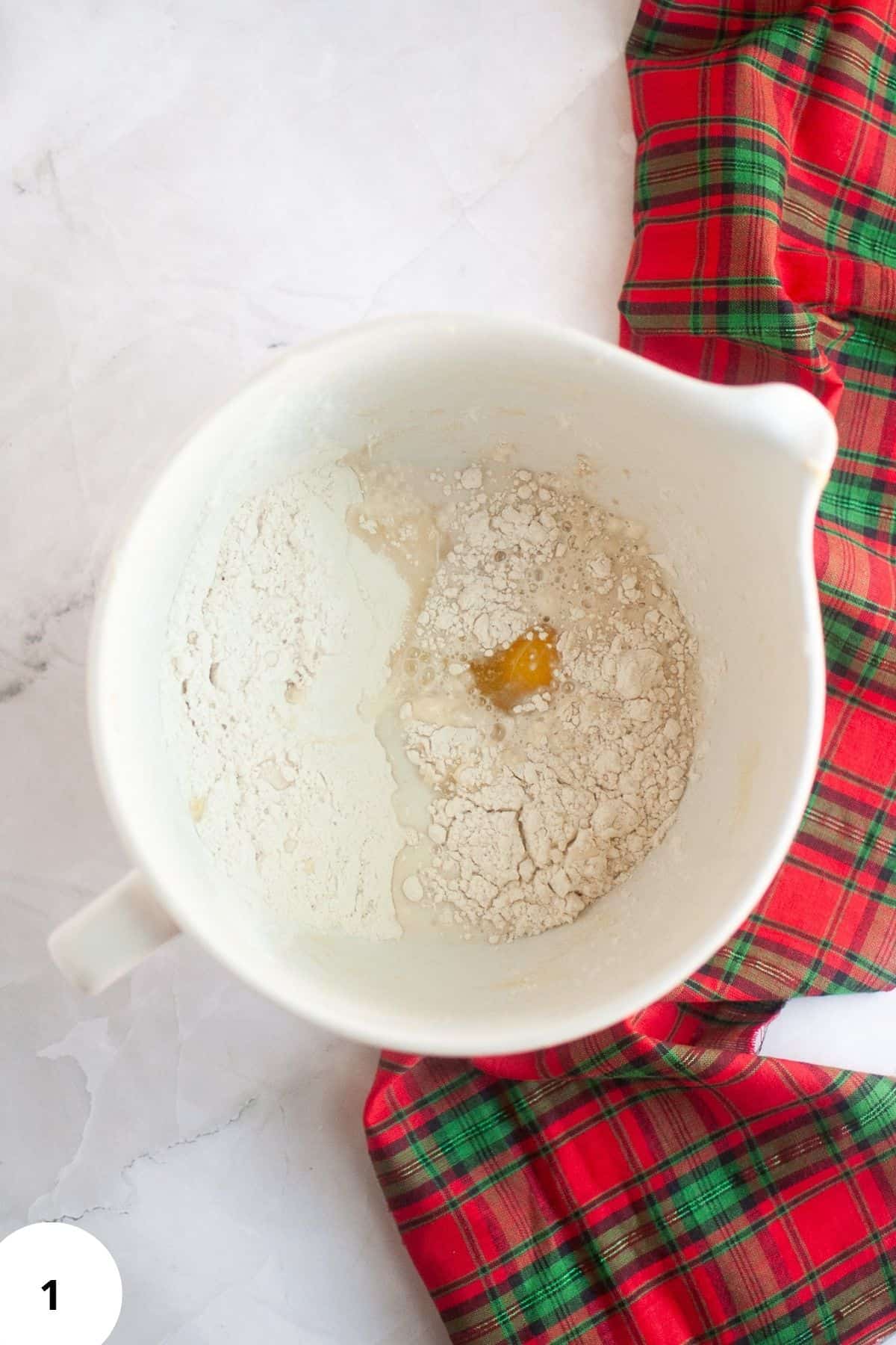 Baking ingredients being mixed together in a mixer during dough preparation.