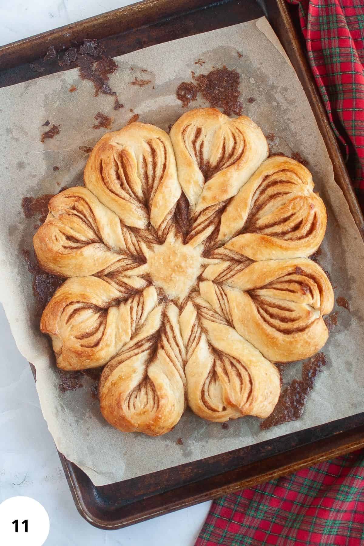 Freshly baked star bread resting on a baking tray lined with parchment paper, showing its golden brown crust.