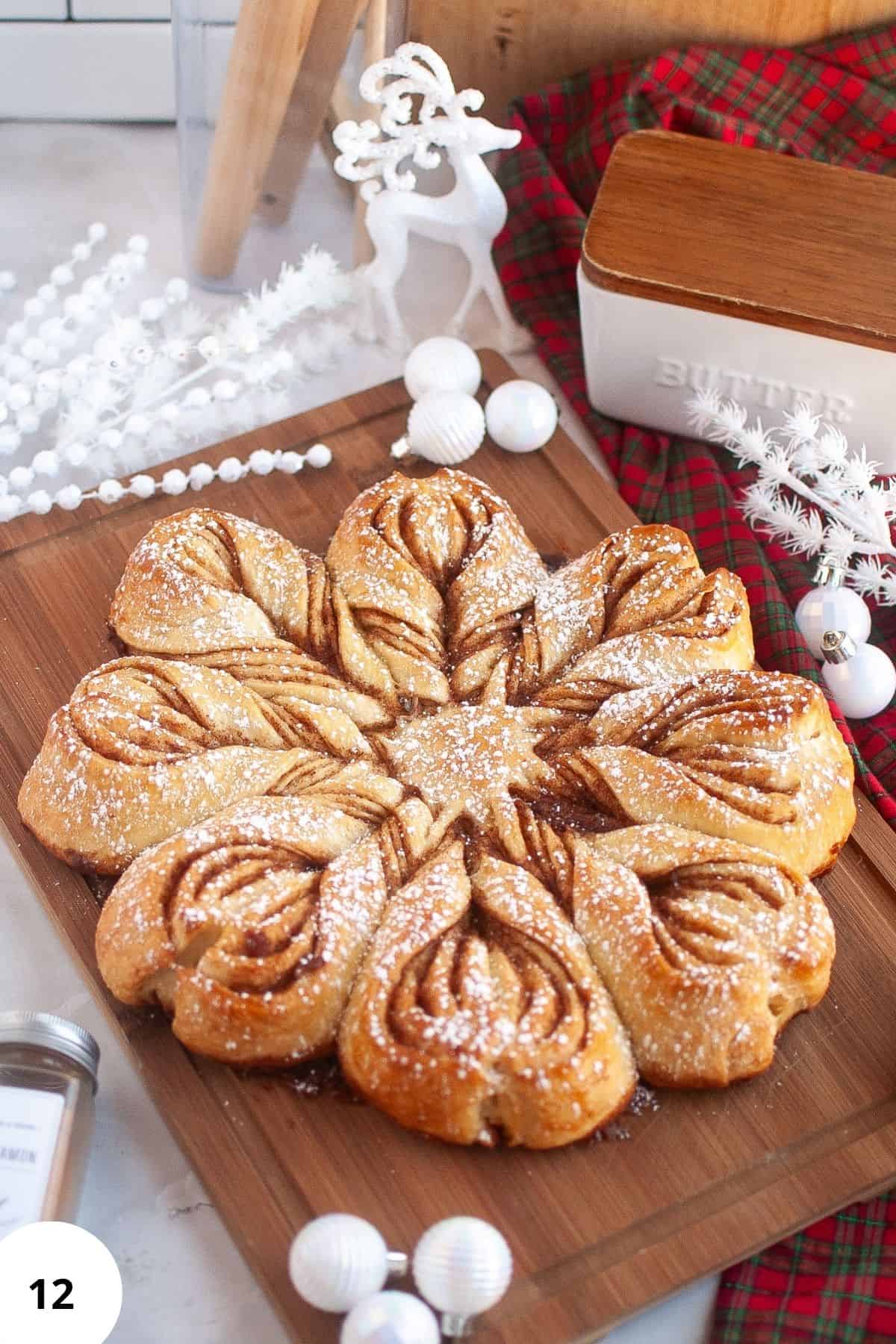 Homemade sourdough star bread displayed on a wooden board, surrounded by festive Christmas ornaments and holiday decorations.