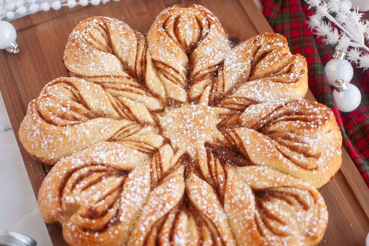 Close-up view of a sourdough star bread placed on a rustic wooden board, showing its golden, flaky texture.