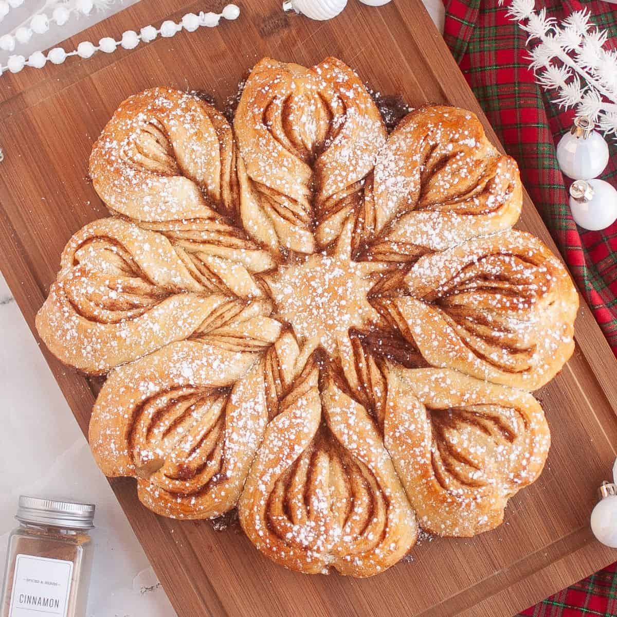 Homemade sourdough star bread displayed on a wooden board, surrounded by festive Christmas ornaments and holiday decorations.