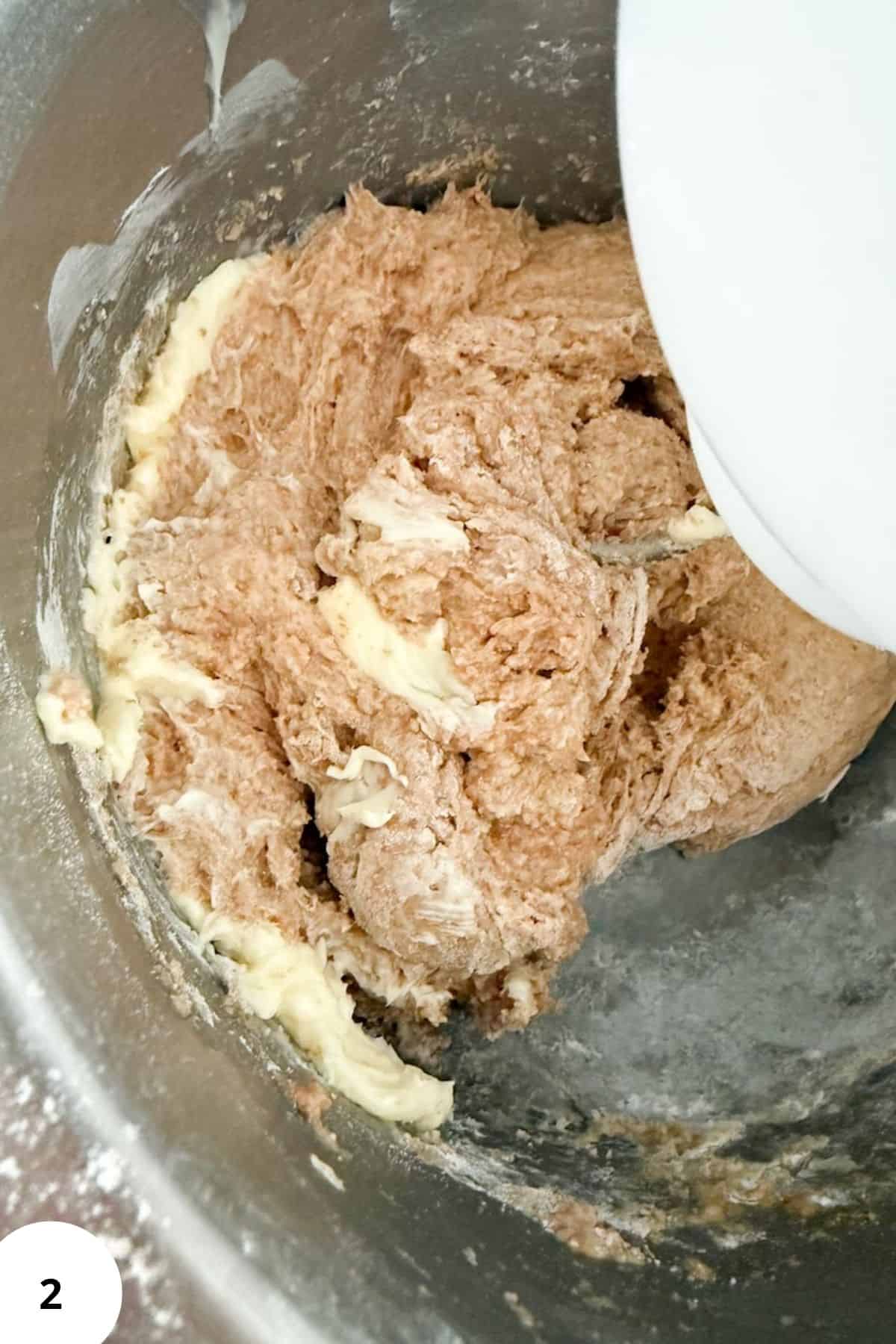Sourdough cinnamon roll dough mixture being mixed in a stand mixer.