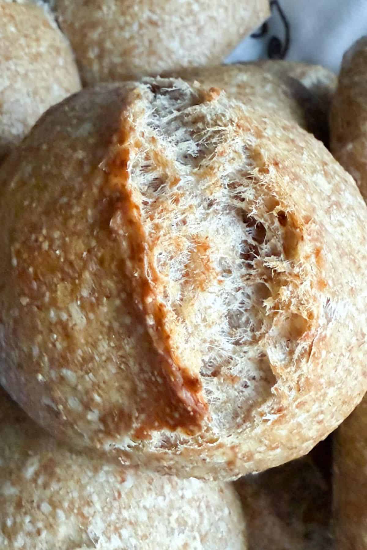 Close-up of freshly baked sourdough rolls stacked on top of each other, showing their golden crust and soft texture.