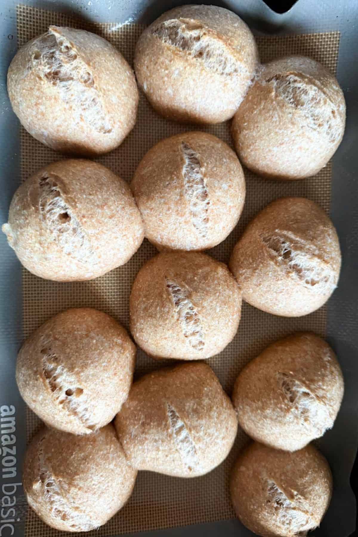 Freshly baked sourdough rolls resting on a wire cooling rack, showing their golden crust and airy texture.