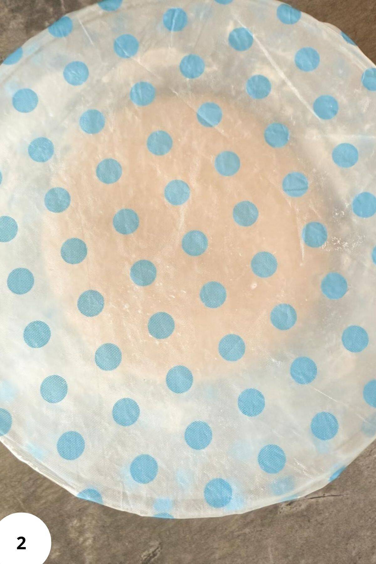 Dough resting in a large bowl covered during fermentation.