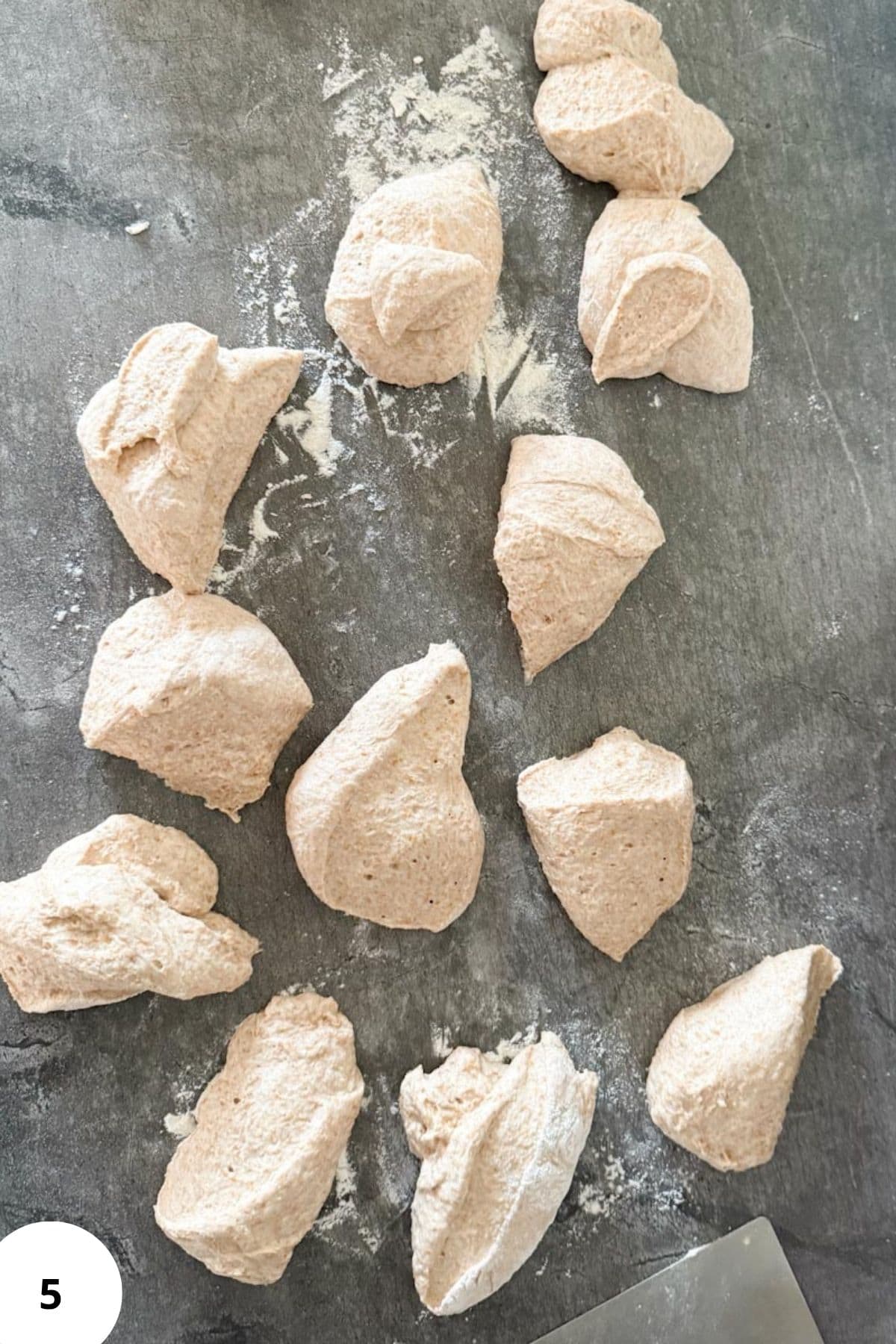 Dough being divided on a floured surface, ready to be shaped into individual rolls.