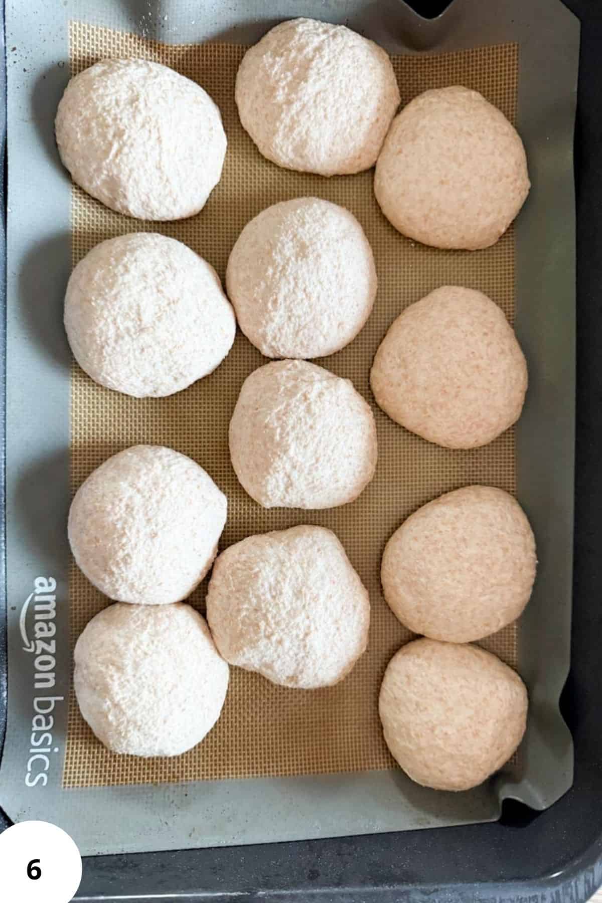 Unbaked sourdough rolls on a parchment-lined baking tray.
