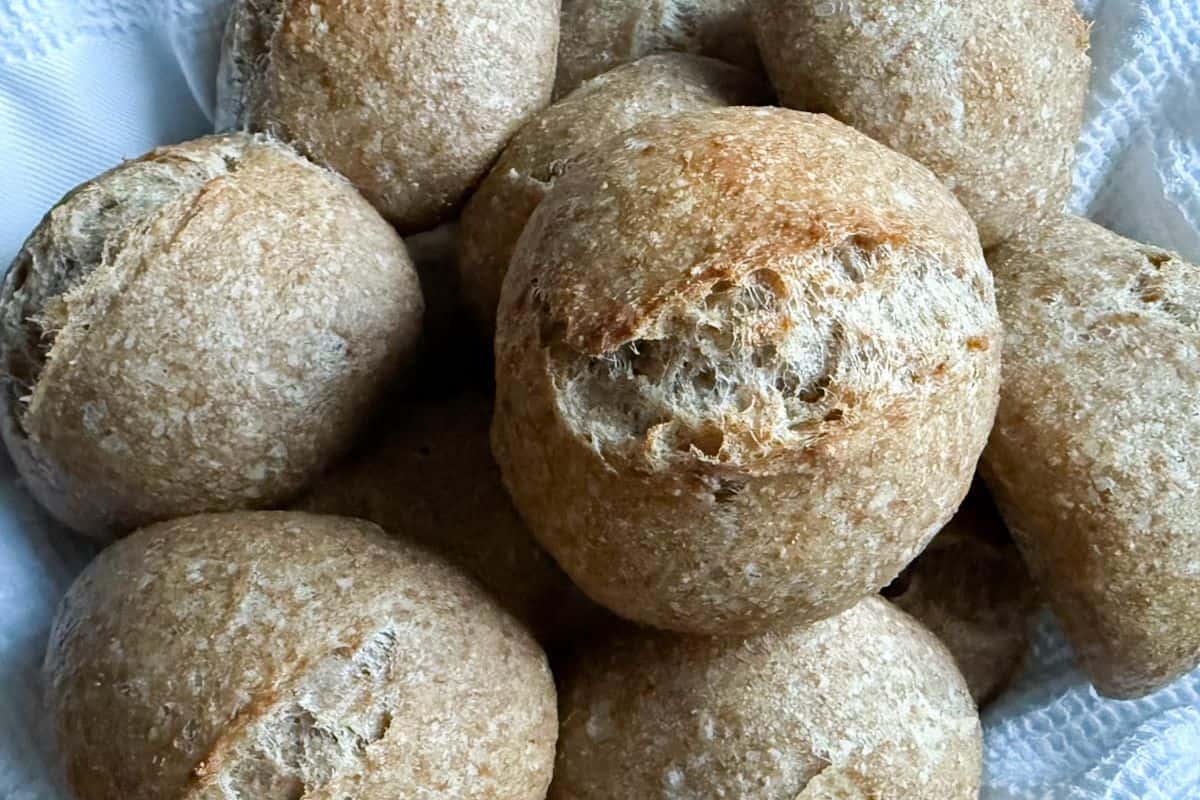 Close-up of freshly baked sourdough rolls stacked on top of each other, showing their golden crust and soft texture.