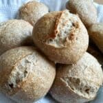 Close-up of freshly baked sourdough rolls stacked on top of each other, showing their golden crust and soft texture.
