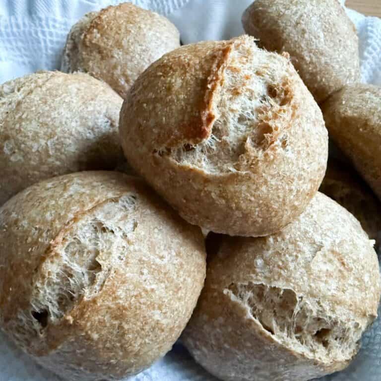 Close-up of freshly baked sourdough rolls stacked on top of each other, showing their golden crust and soft texture.
