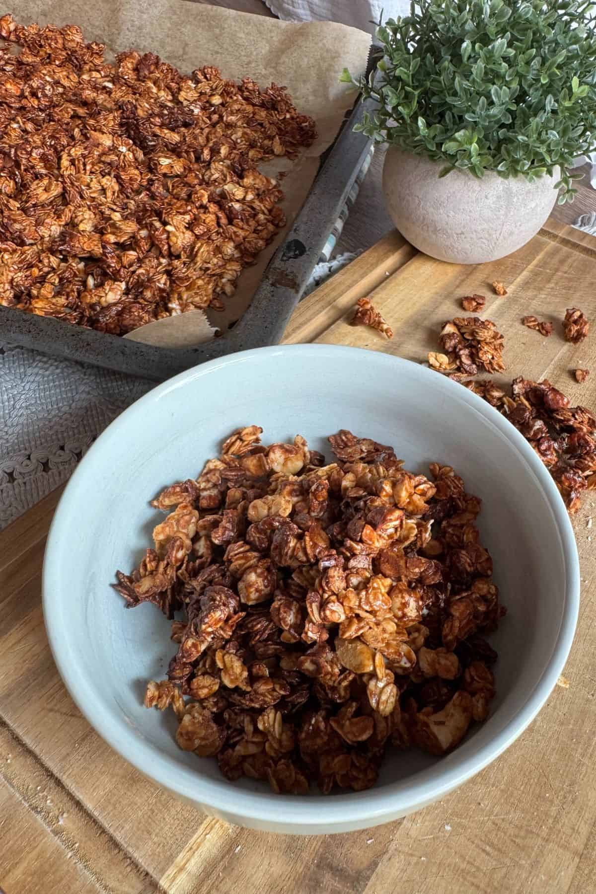 Sourdough granola served in a bowl, with extra granola in a baking dish nearby.