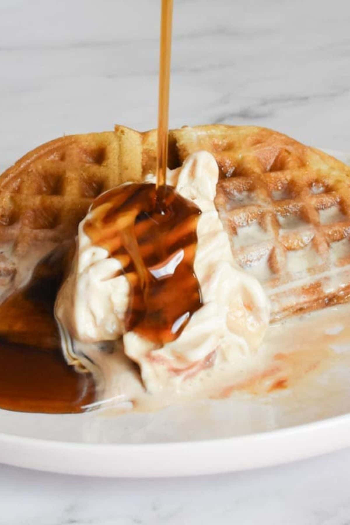 Delicious waffles topped with whipped cream and drizzled with syrup, perfect for breakfast.