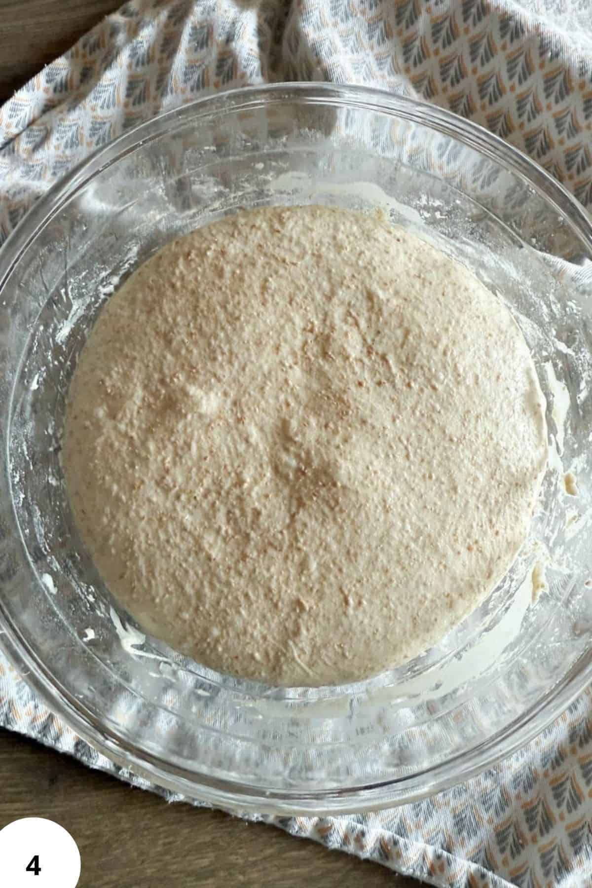 Fresh milled grain dough in glass bowl ready for baking, promoting nutritious homemade recipes.