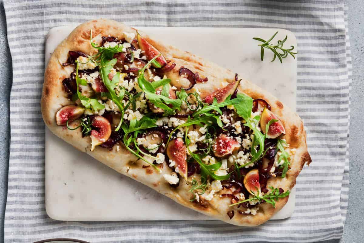 Delicious flatbread topped with herbs, cheese, and vegetables, showcasing perfect stretch and folds in bread baking.