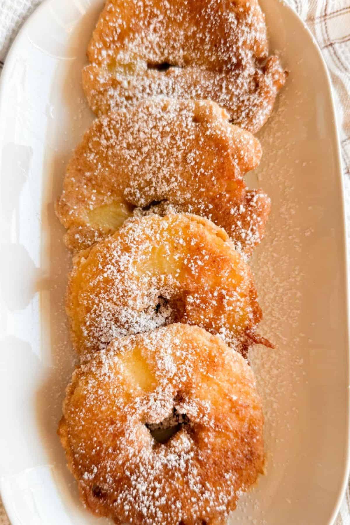 Delicious homemade apple donuts coated with powdered sugar, made with fresh milled ingredients.