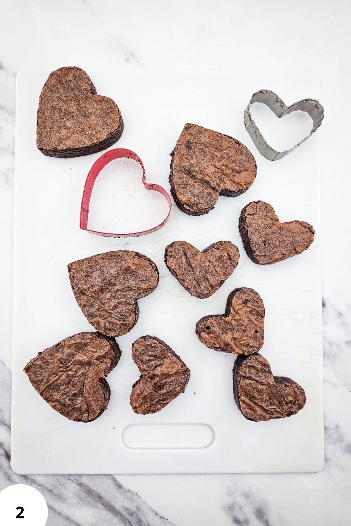 Heart-shaped cookies and metal cookie cutters on a baking surface, perfect for Valentine's Day baking.