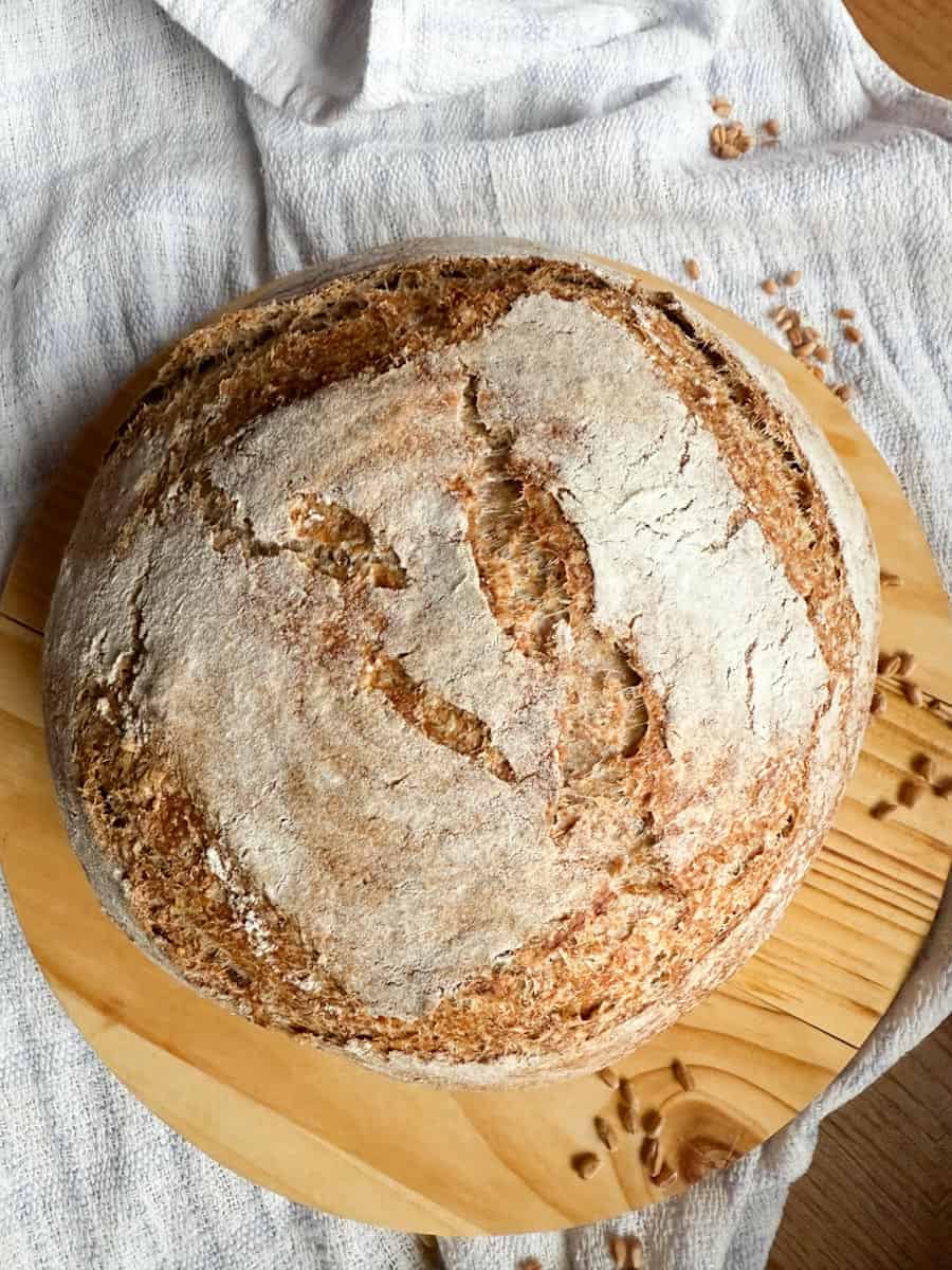 Round sourdough bread with crusty exterior on a wooden board.
