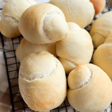 Delicious homemade bread rolls on a cooling rack, showcasing a perfect proof and crust, great for bread lovers.