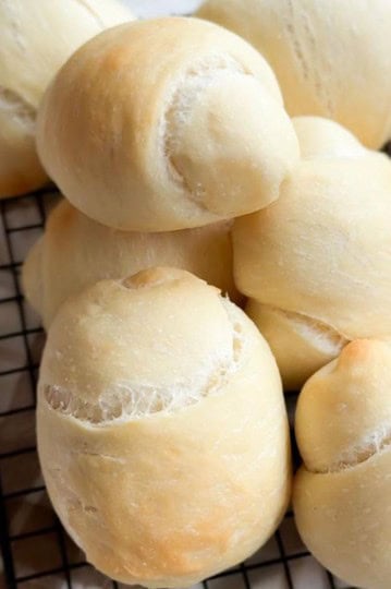 Delicious homemade bread rolls on a cooling rack, showcasing a perfect proof and crust, great for bread lovers.