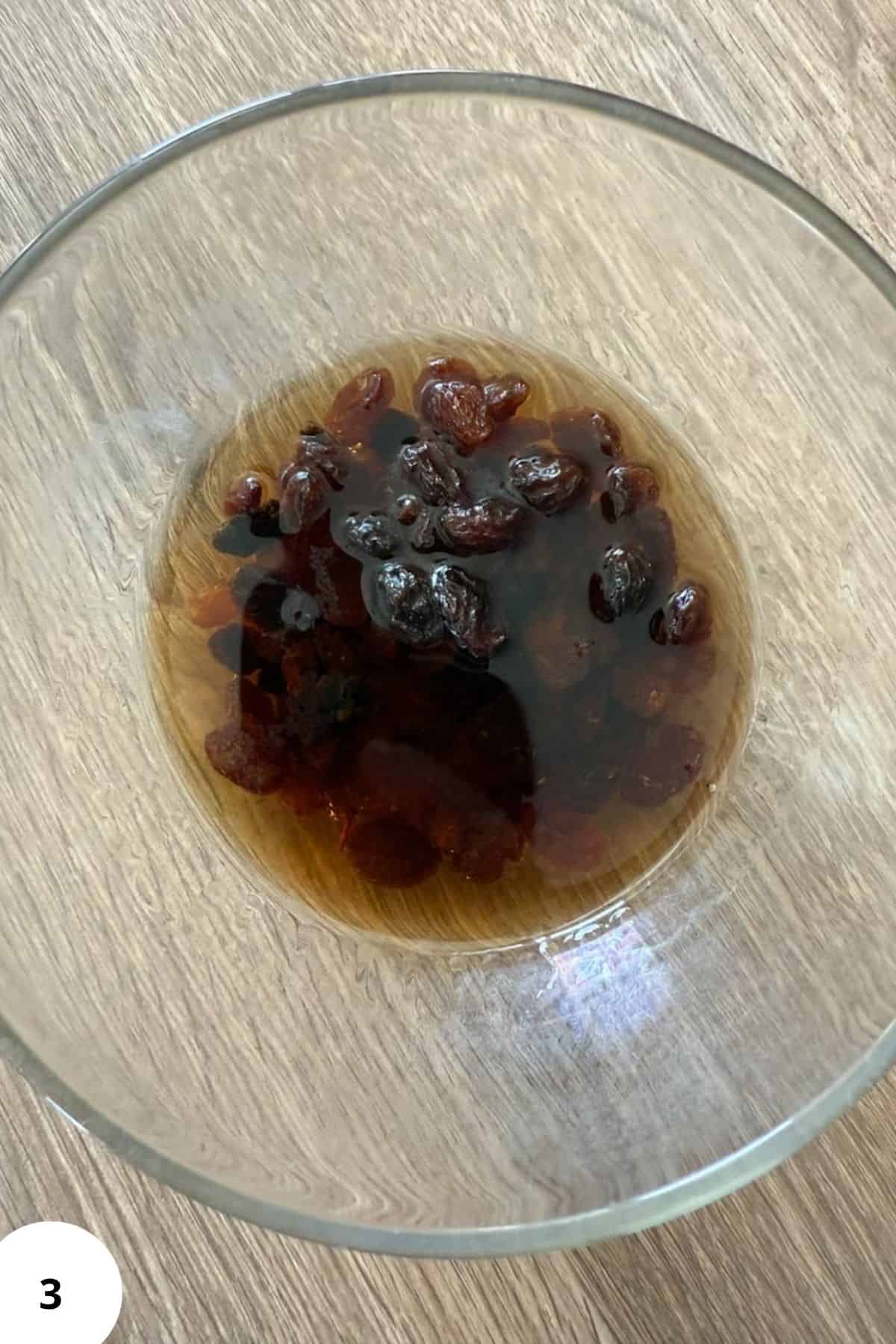 Close-up of shredded pancake topping with raisins in a glass bowl.