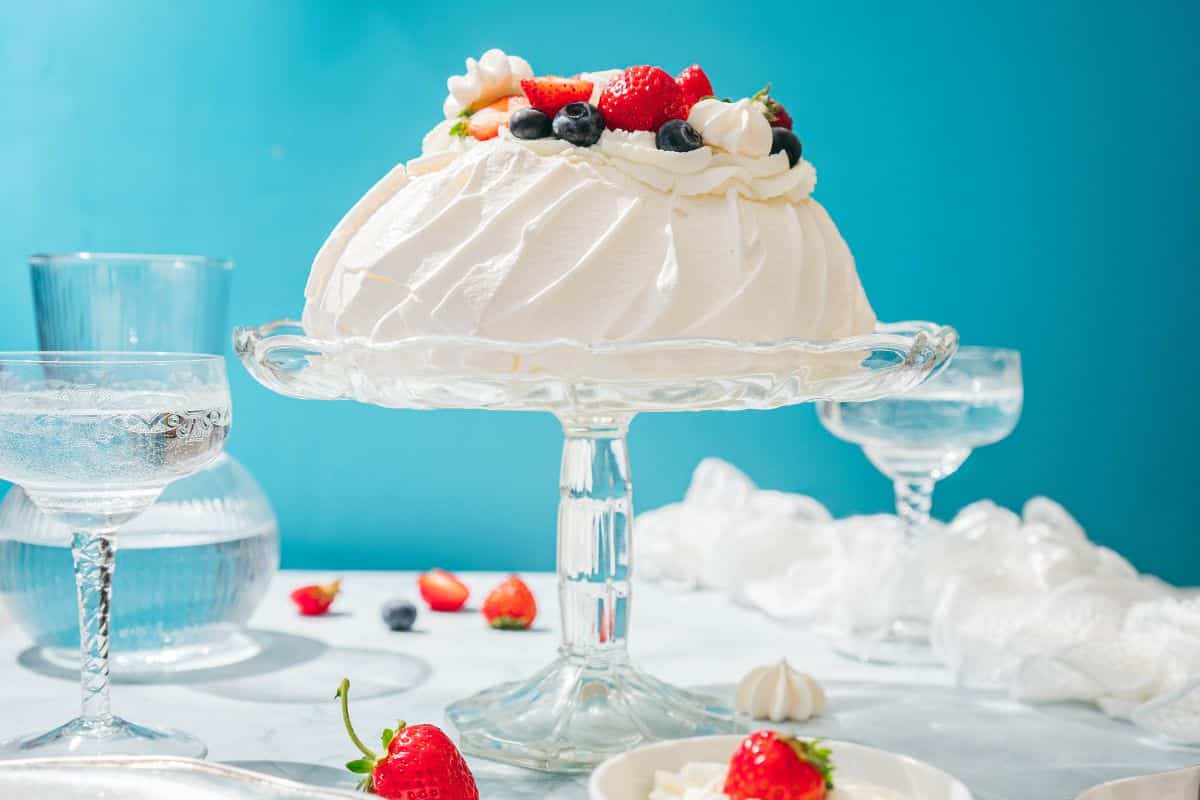 Elegant meringue cake topped with fresh strawberries and mixed berries, perfect for desserts or celebrations.