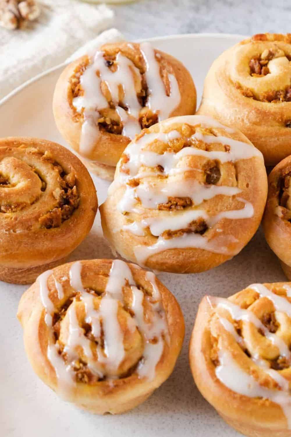 Delicious homemade cinnamon rolls topped with icing and chopped nuts, perfect for breakfast or dessert.