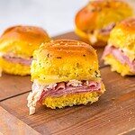 Delicious focaccia bread with ham, cheese, herbs, served as sandwiches on a rustic wooden surface.