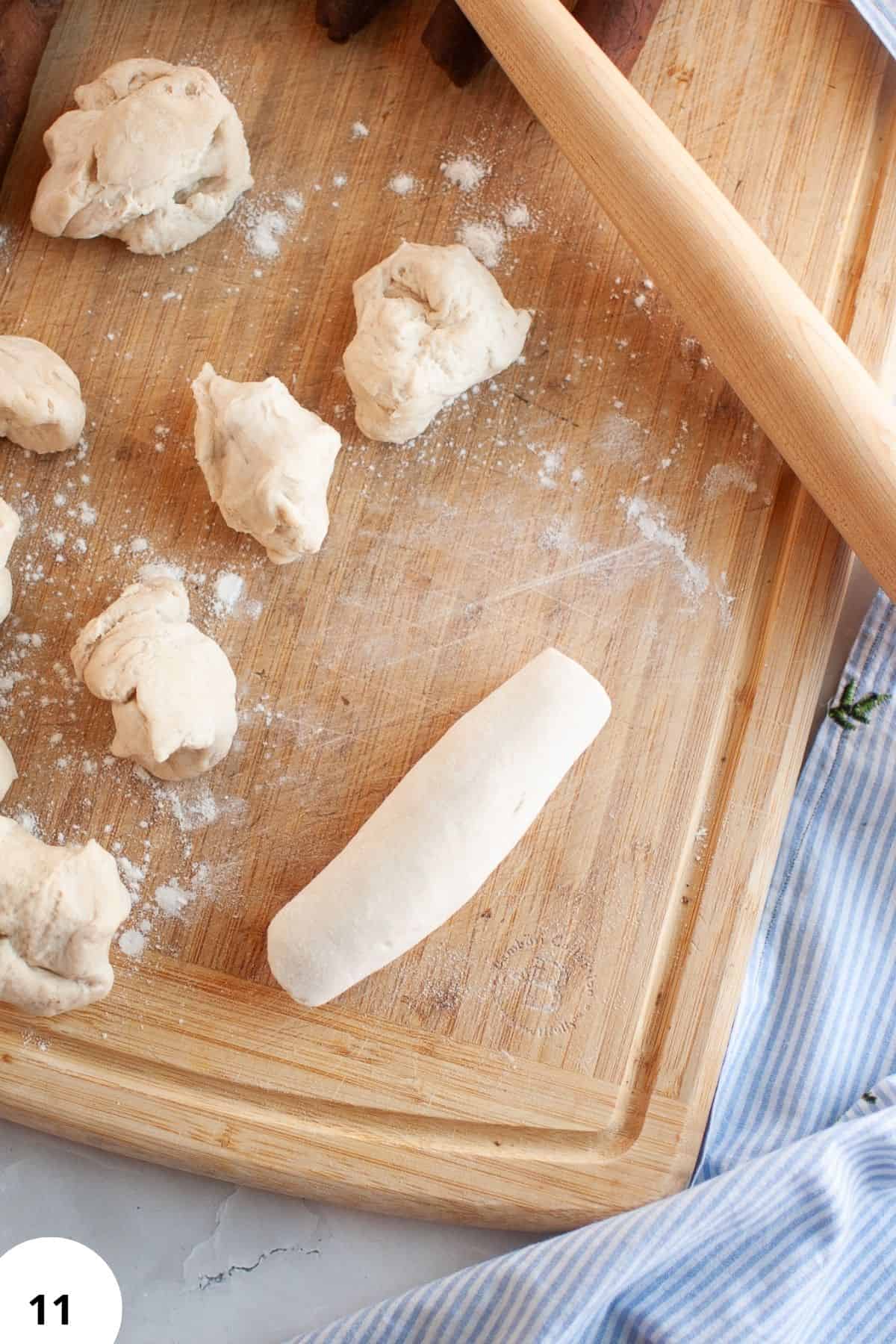 Dough balls and a rolling pin on a wooden board for sourdough bread baking.