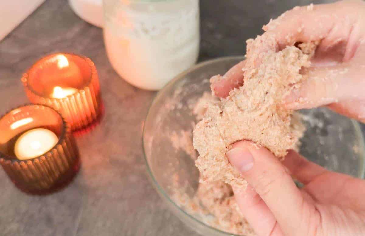 Hands mixing flour and water for bread dough in a bowl.