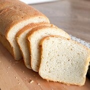 Artisan bread with a soft, airy crumb and golden crust on a wooden cutting board.