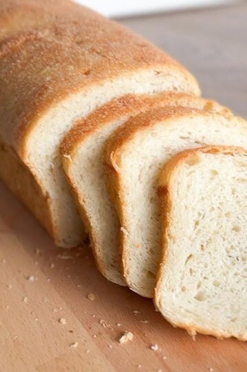 Artisan bread with a soft, airy crumb and golden crust on a wooden cutting board.