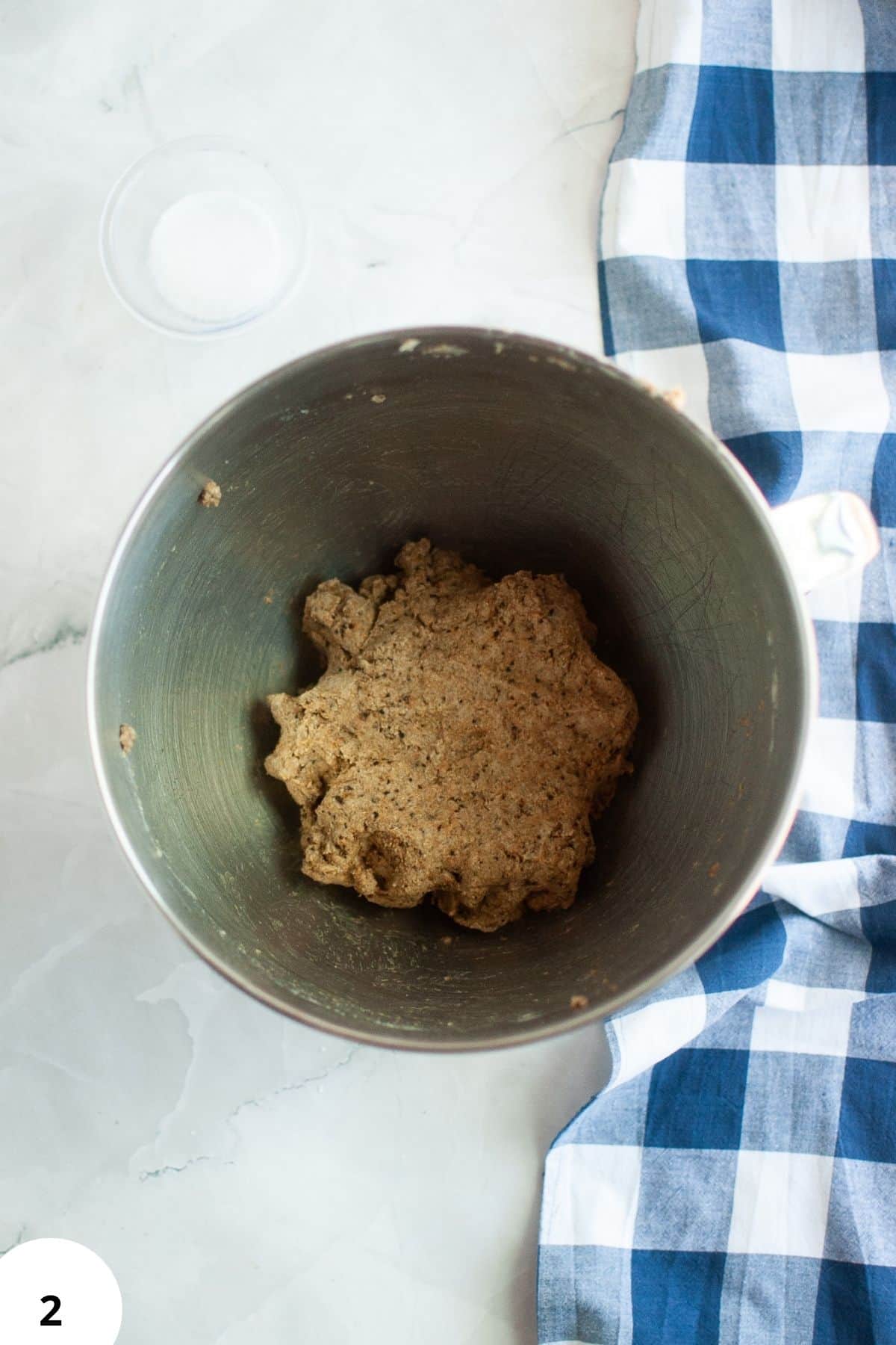 Al text: Fermentation dough for sourdough bread in mixing bowl with blue cloth nearby.