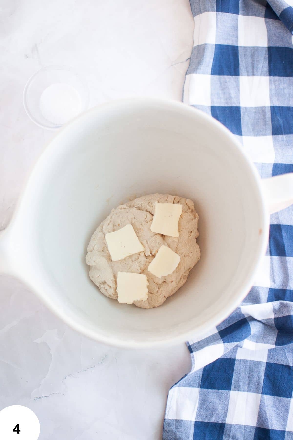 Artisan bread dough in a mixing bowl with butter pieces, ideal for stretching and folding.