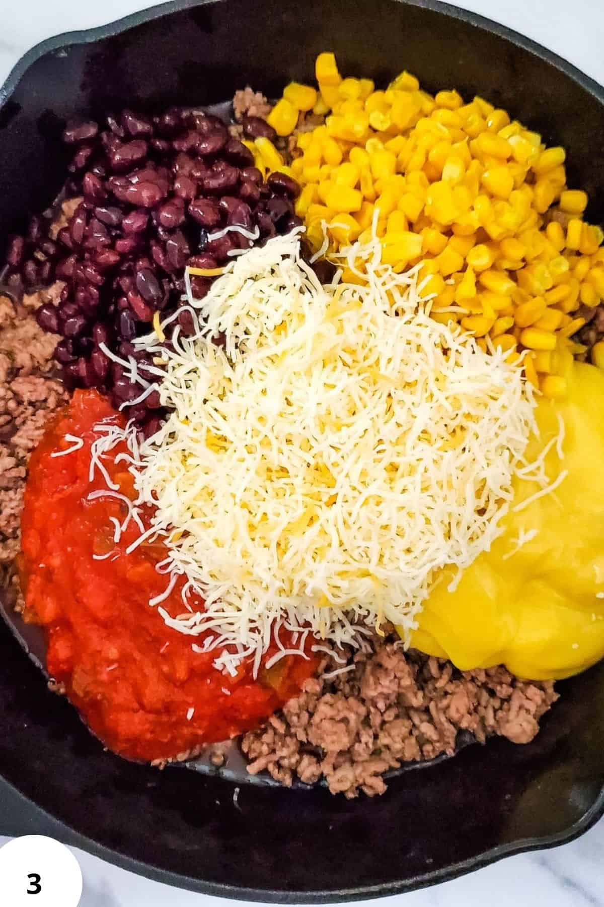 Colorful mixture of beans, corn, ground beef, and shredded cheese in a pan.