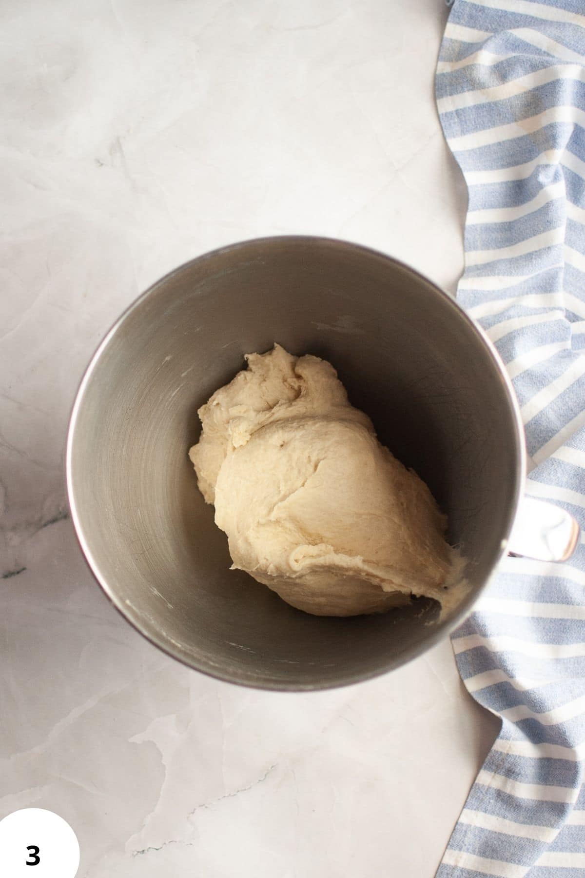 Bread dough in a metal mixing bowl, ready for fermentation and rising.
