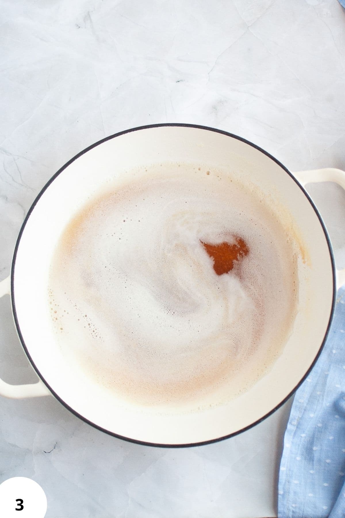 Close-up of bubbling yeast mixture in a white enamel bowl, ready for bread fermentation process.