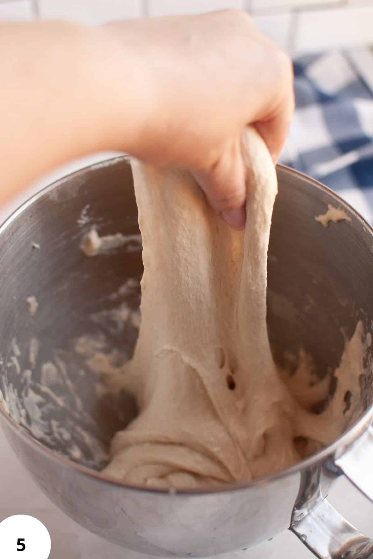 Artisan sourdough dough being stretched and folded in a mixing bowl for bread baking.