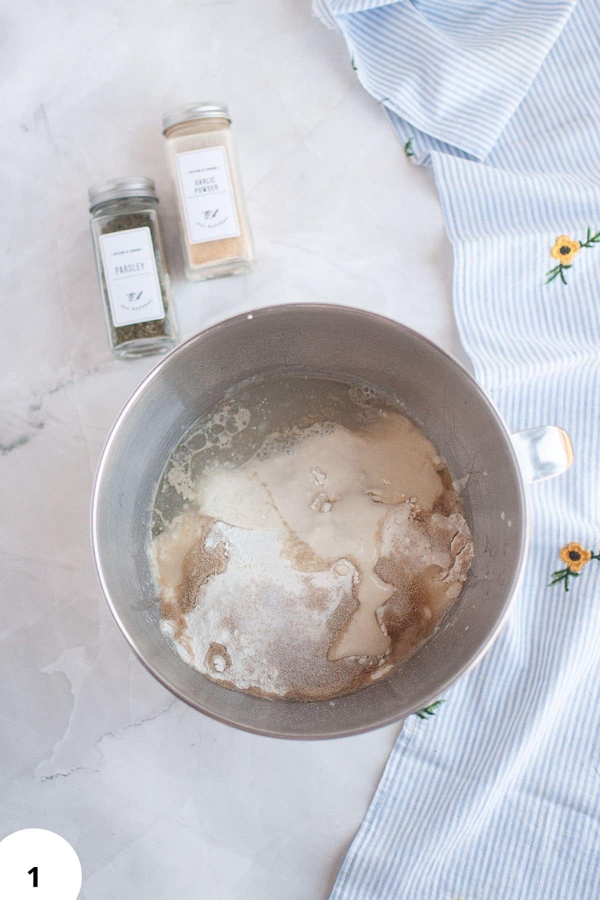Proofing dough with ingredients like yeast, flour, and water on a marble surface.