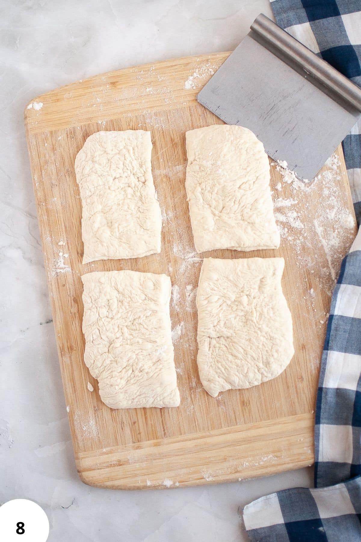 Image shows four rectangular dough pieces on a wooden cutting board, ready for stretching and folding.