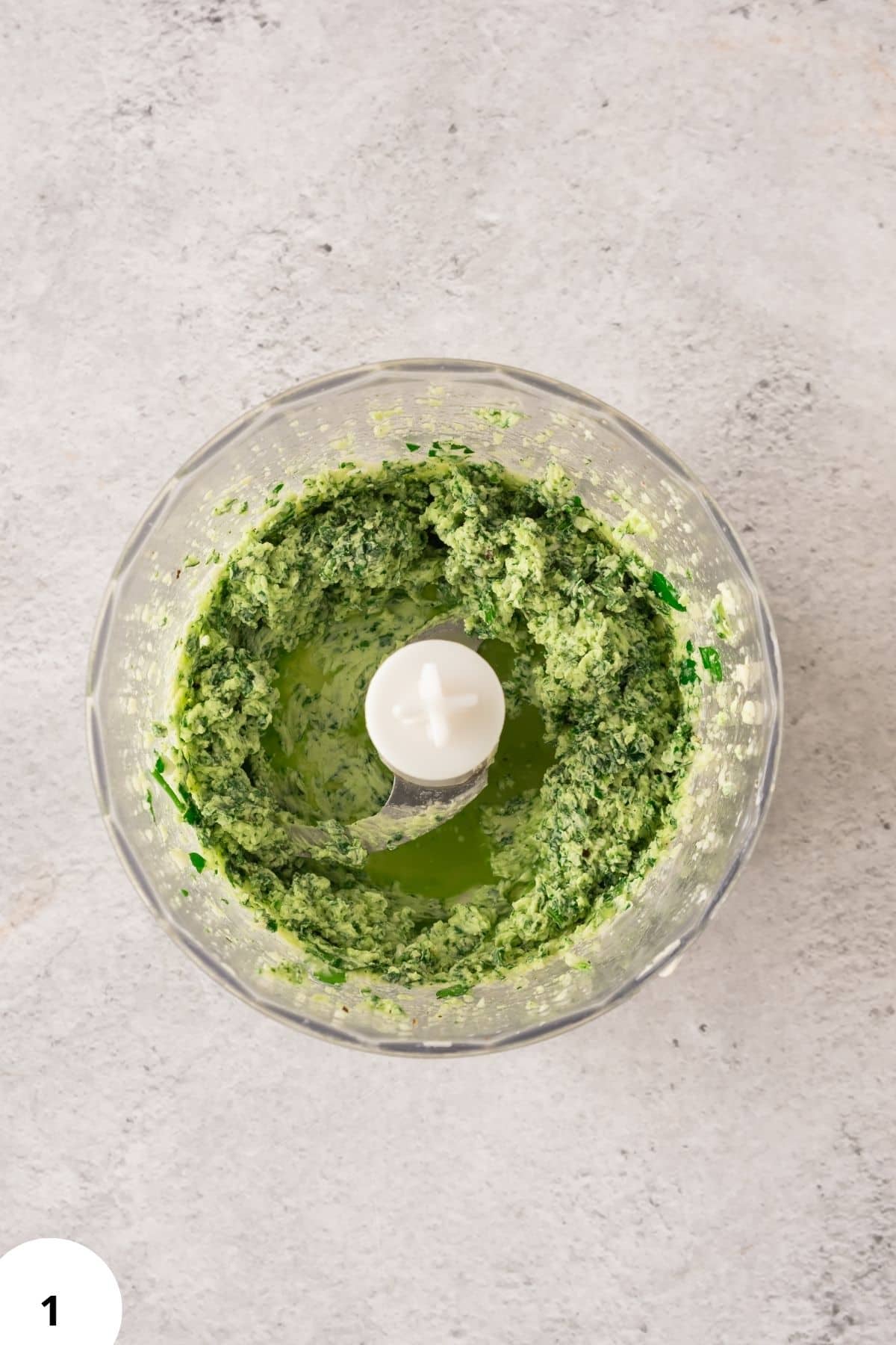 Fresh green herb dough mix in food processor, perfect for bread or pizza recipes.
