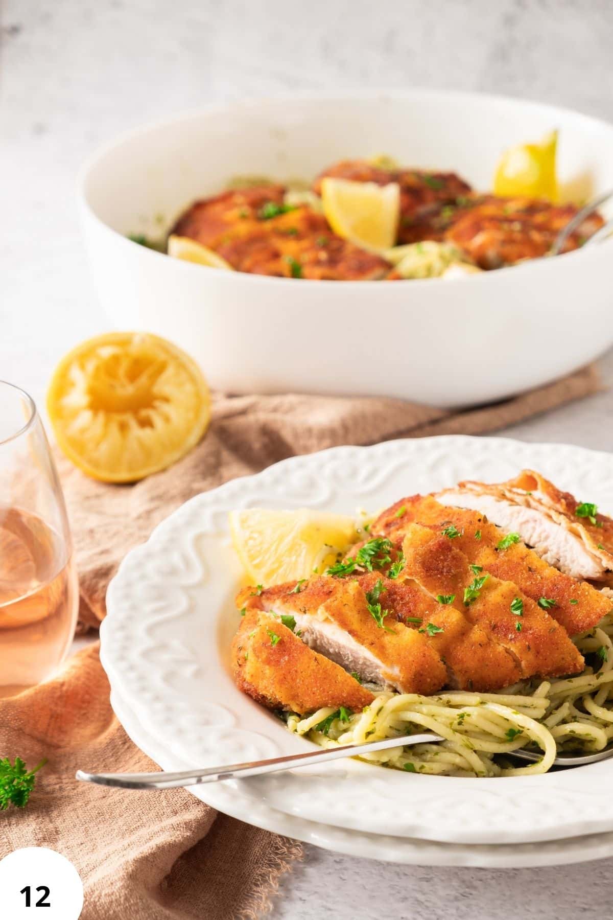 Delicious chicken parmesan dish served with spaghetti and lemon wedges for added flavor.