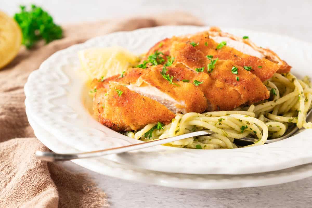 Golden fried chicken served over spaghetti with herbs, garnished with lemon and parsley. Perfect comfort food.