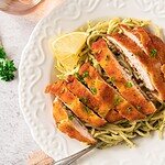 Delicious bread loaf with lemon slices served over spaghetti pasta on elegant white plate.