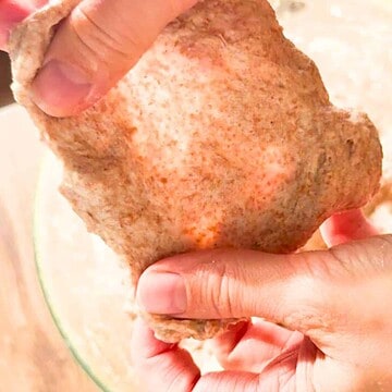 Close-up of hands performing stretch and fold on bread dough.