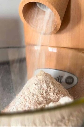 Close-up of fresh-milled flour being poured into a glass bowl.