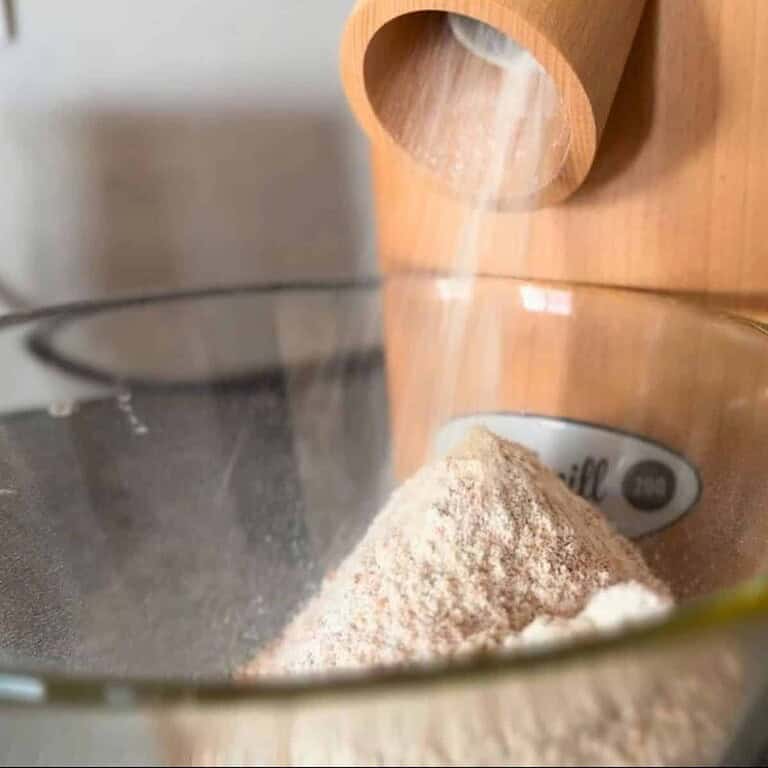 Close-up of fresh-milled flour being poured into a glass bowl.