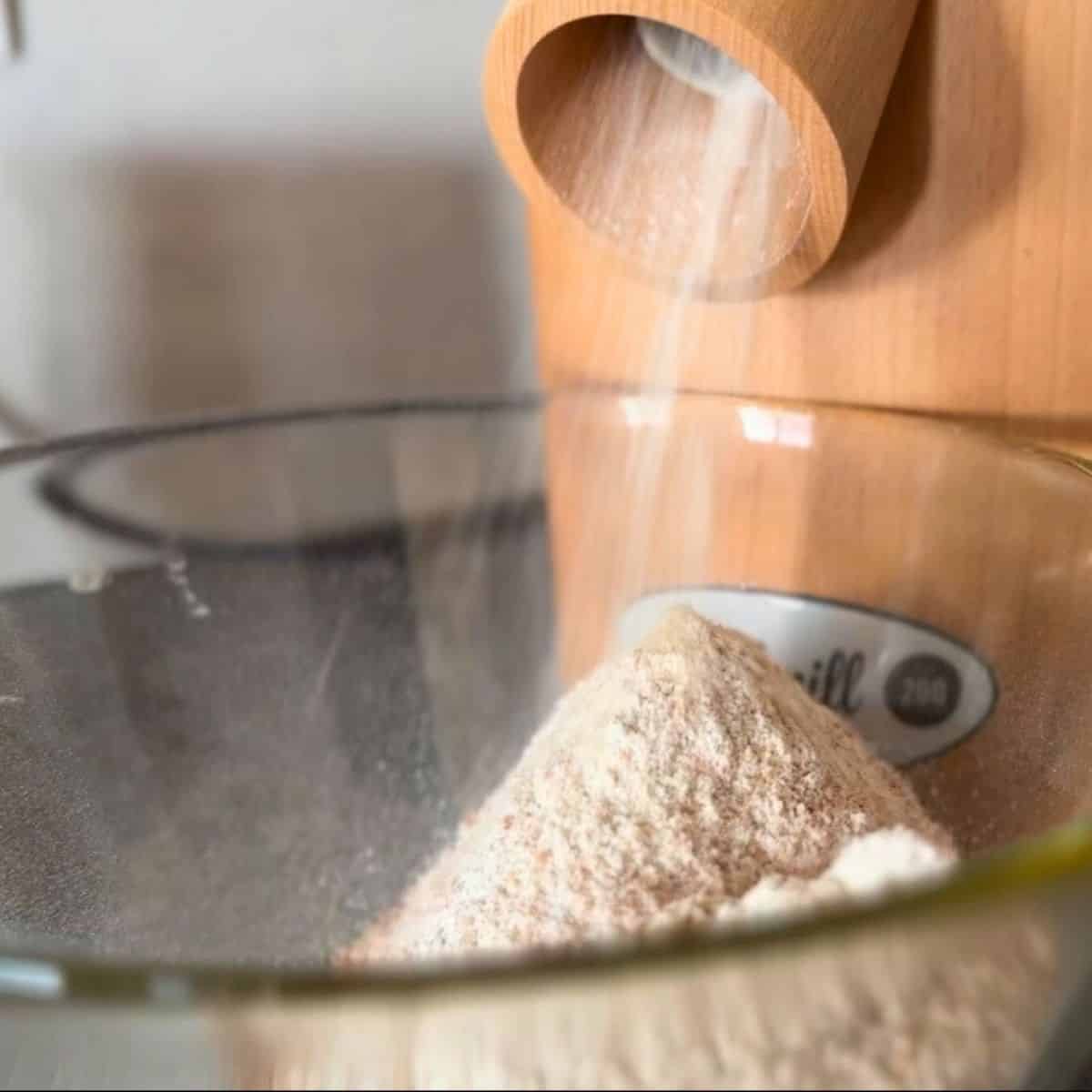 Close-up of fresh-milled flour being poured into a glass bowl.