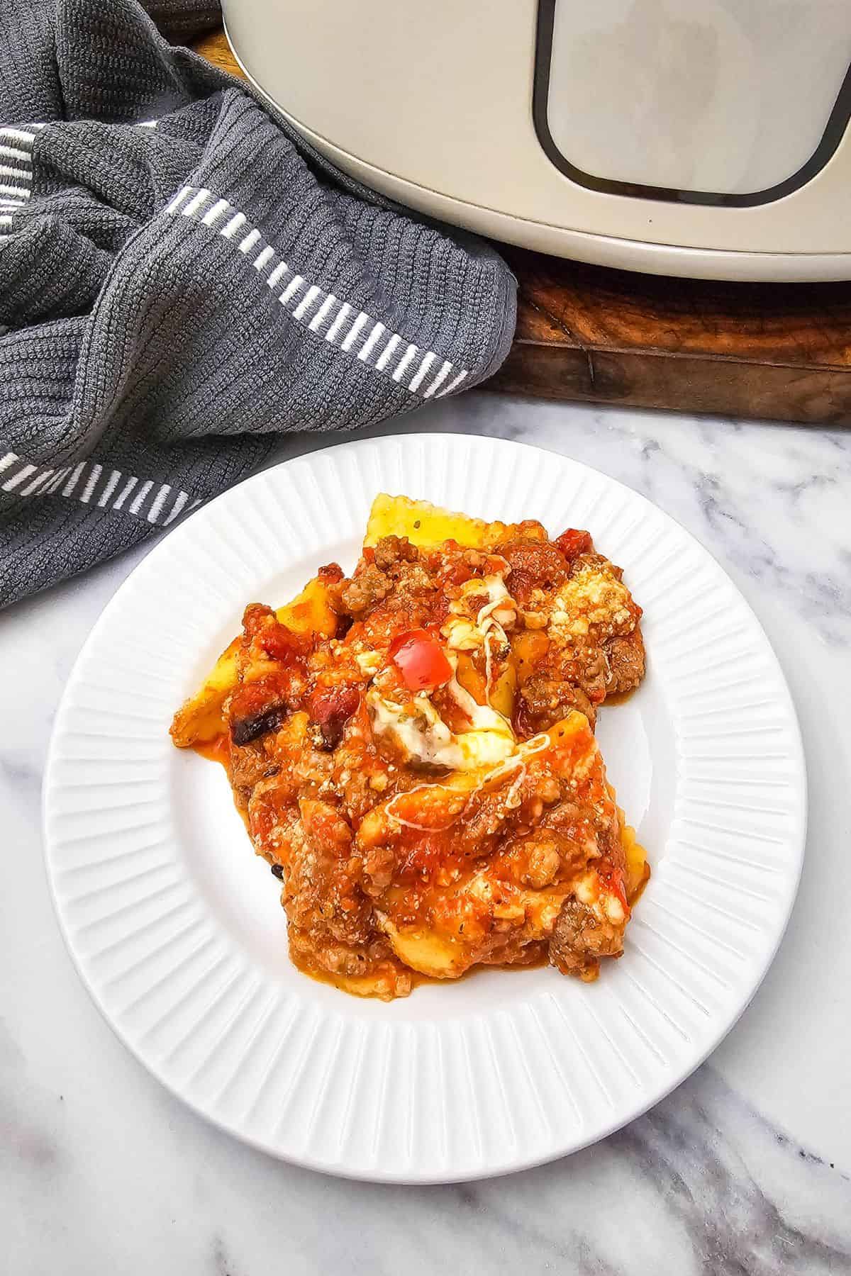 Freshly baked fruit crumble on a white plate with a gray cloth nearby.