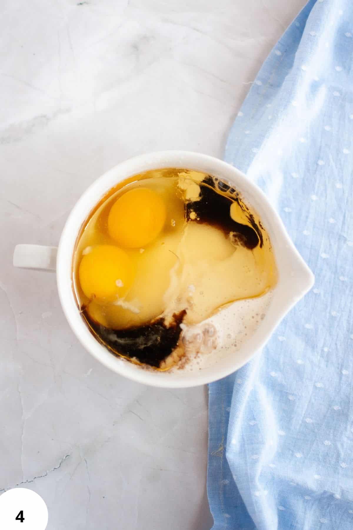 Sourdough dough with stretch and folds process in a white bowl on marble surface.